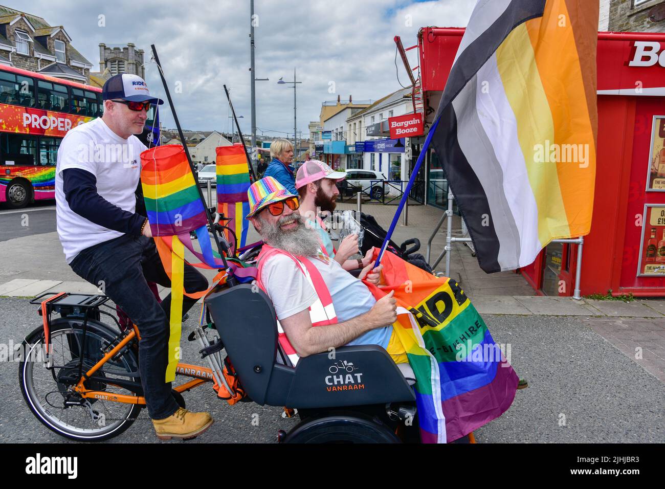 I partecipanti che cavalcano in un risciò di Van Raam Electric Chat nella vivace e colorata Cornovaglia premia la sfilata Pride nel centro di Newquay nel Regno Unito. Foto Stock