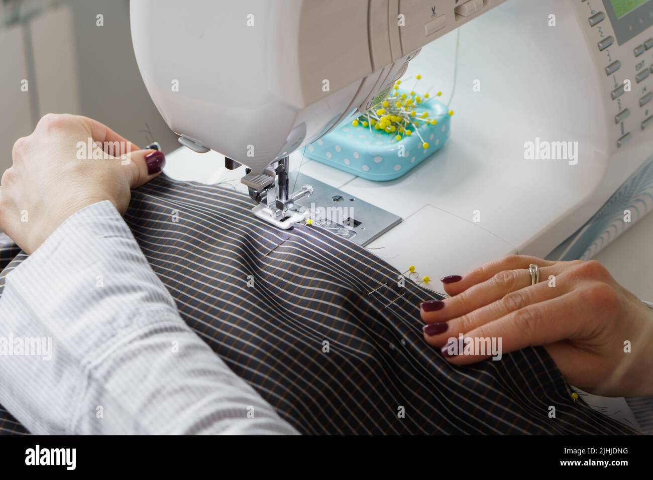 La donna di seamstress lavora sulla macchina da cucire. Le mani del dressaker lavorano alla fabbrica di cucire Foto Stock