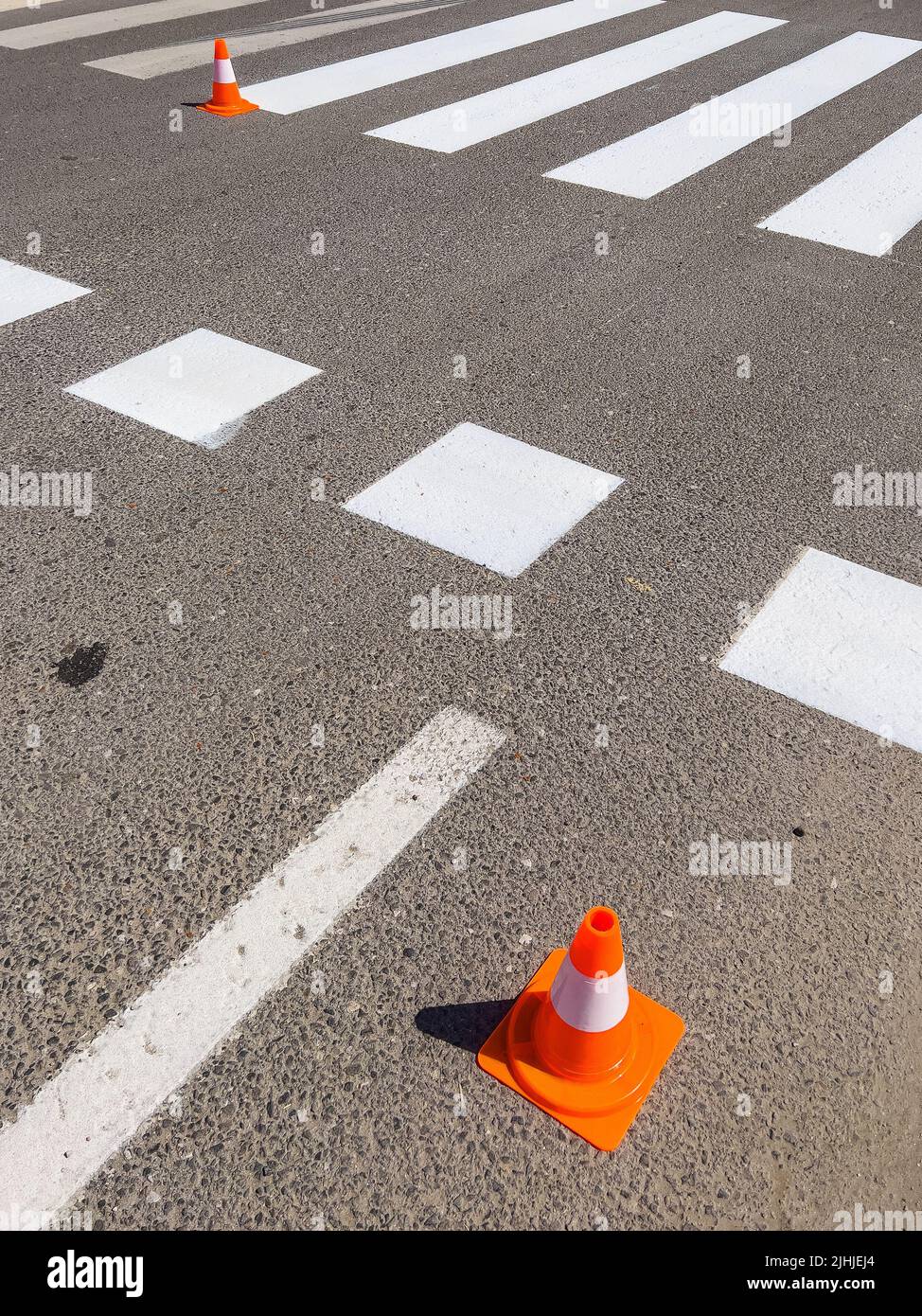 Vernice di marchiatura Zebra sulla strada e cono di traffico arancione sulla strada Foto Stock