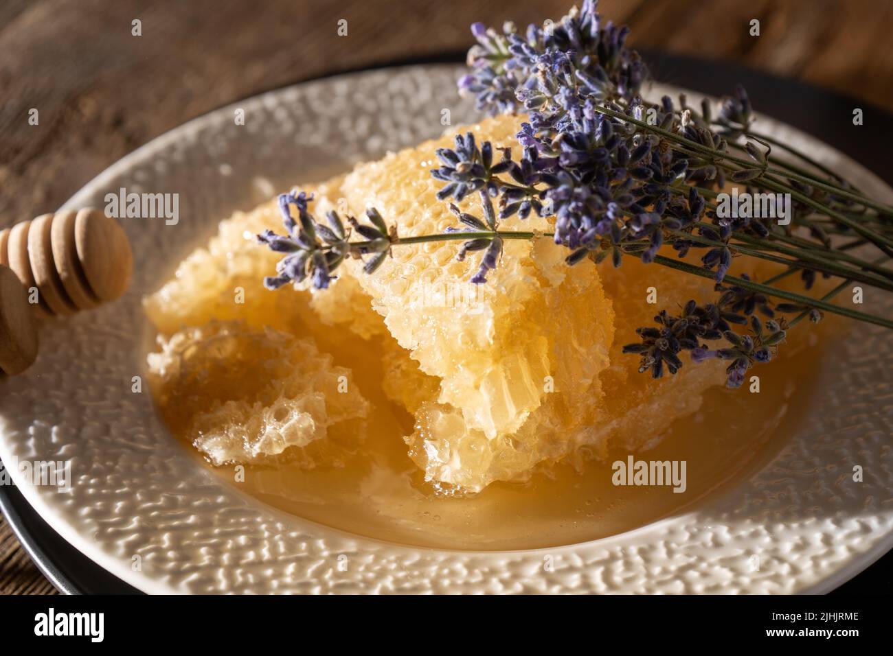 Miele e nido d'ape su un piatto bianco. Cibo dolce in una ciotola sul tavolo. Un prodotto dell'apicoltura. Fiore di lavanda. Foto Stock