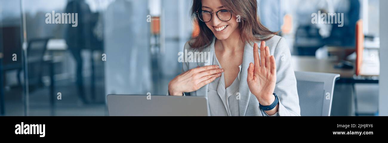 Donna d'affari sorda sicura che comunica in videochiamata con il cliente in un ufficio moderno Foto Stock