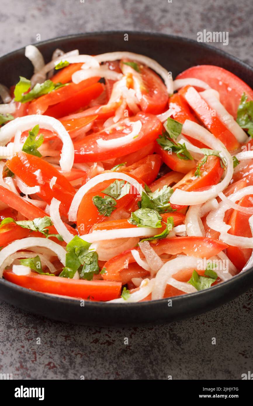 Ensalada chilena è un'insalata cilena composta da pomodori, cipolle, olio d'oliva e coriandolo in primo piano nel piatto sul tavolo. Verticale Foto Stock