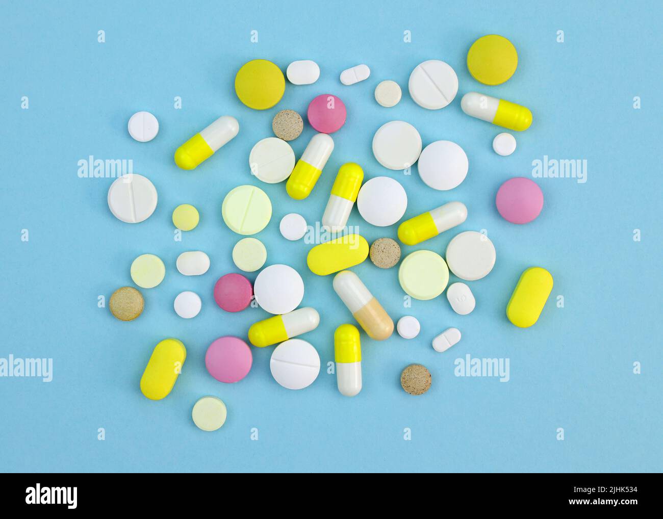 Pillole di diverse dimensioni e colori su sfondo blu. Vista dall'alto colorata delle capsule e delle compresse. Integratori alimentari di vario tipo. Foto Stock