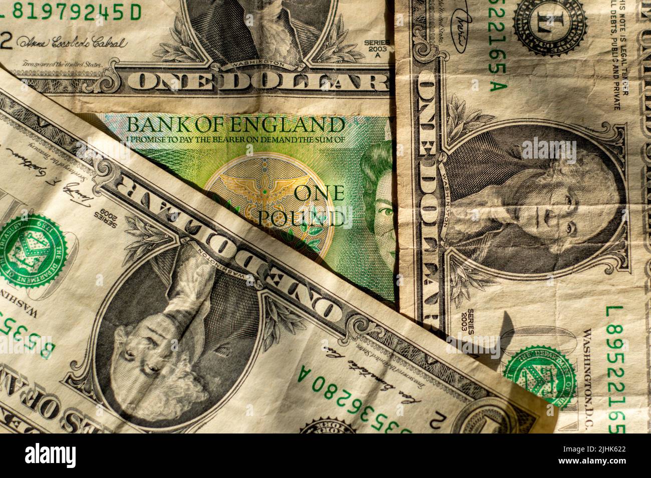 Le vecchie fatture del dollaro circondano una vecchia banconota inglese. La faccia delle Regine sulla vecchia libbra nota è metà coperta e sbirciate fuori da dietro un dollaro fattura. Foto Stock