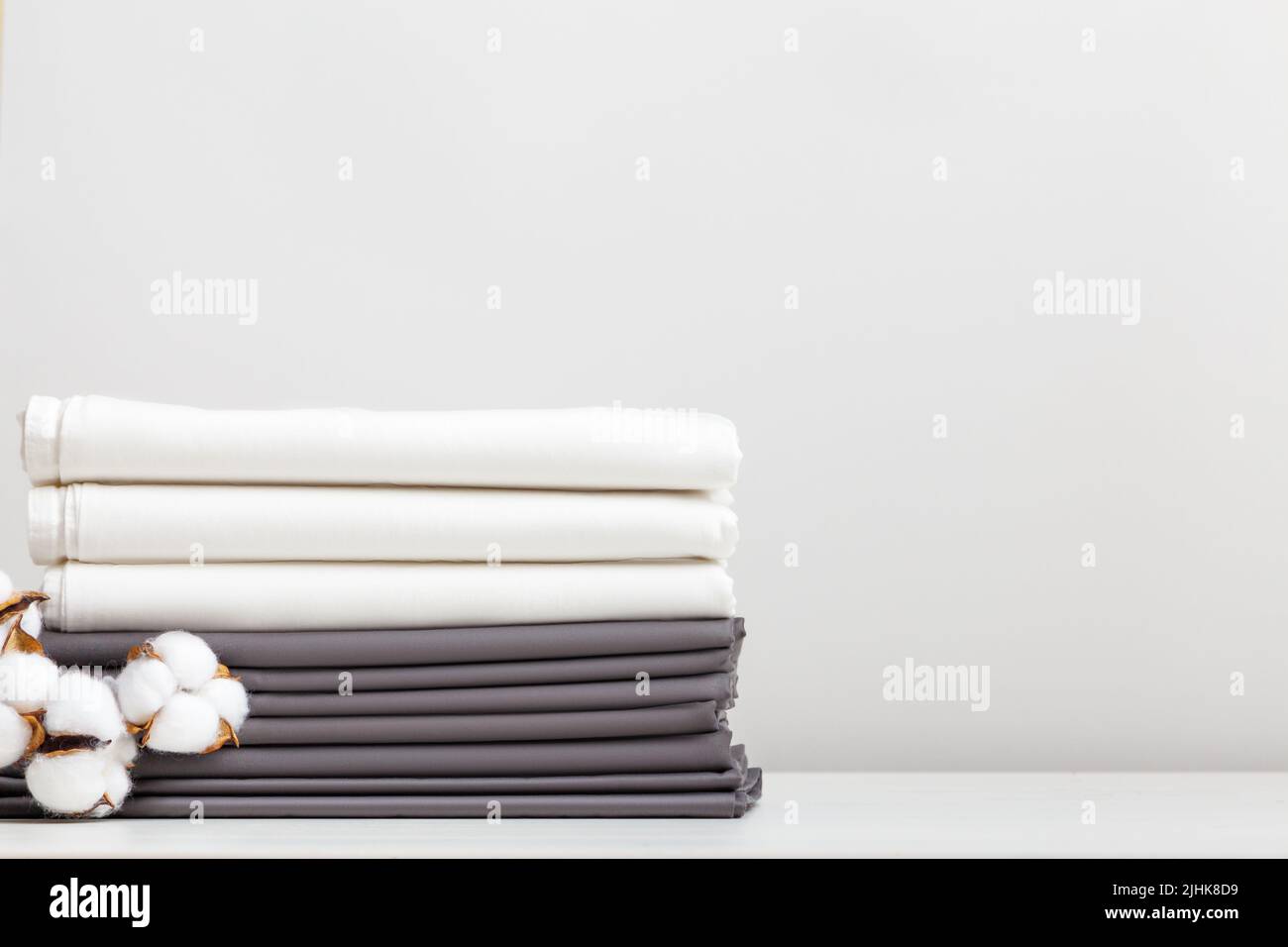 Biancheria da letto grigia e bianca, lenzuola in cotone sul tavolo Foto Stock