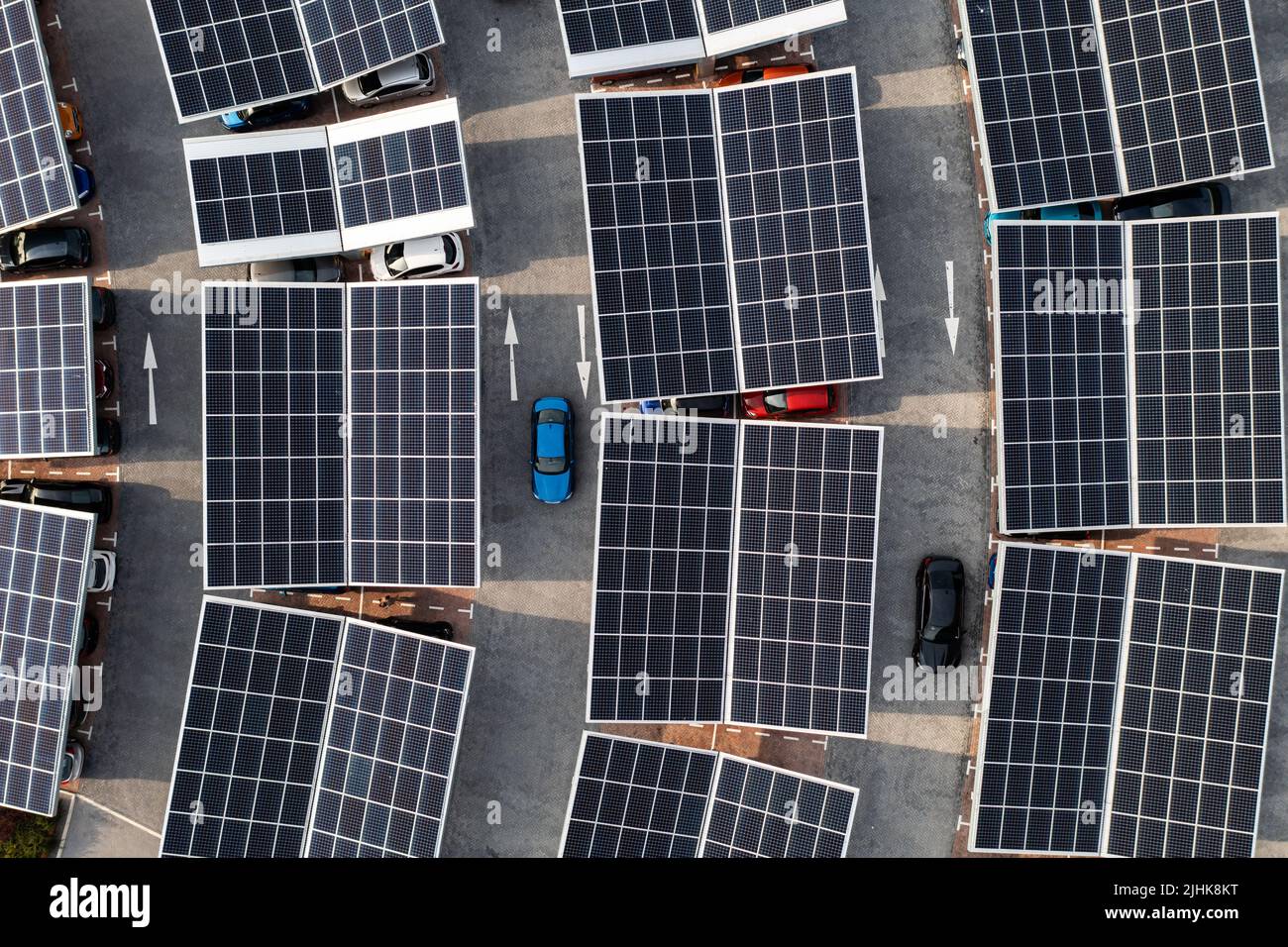 Vista aerea direttamente sopra auto elettriche parcheggio sotto pannelli solari su un parcheggio tetto pronto per la ricarica Foto Stock