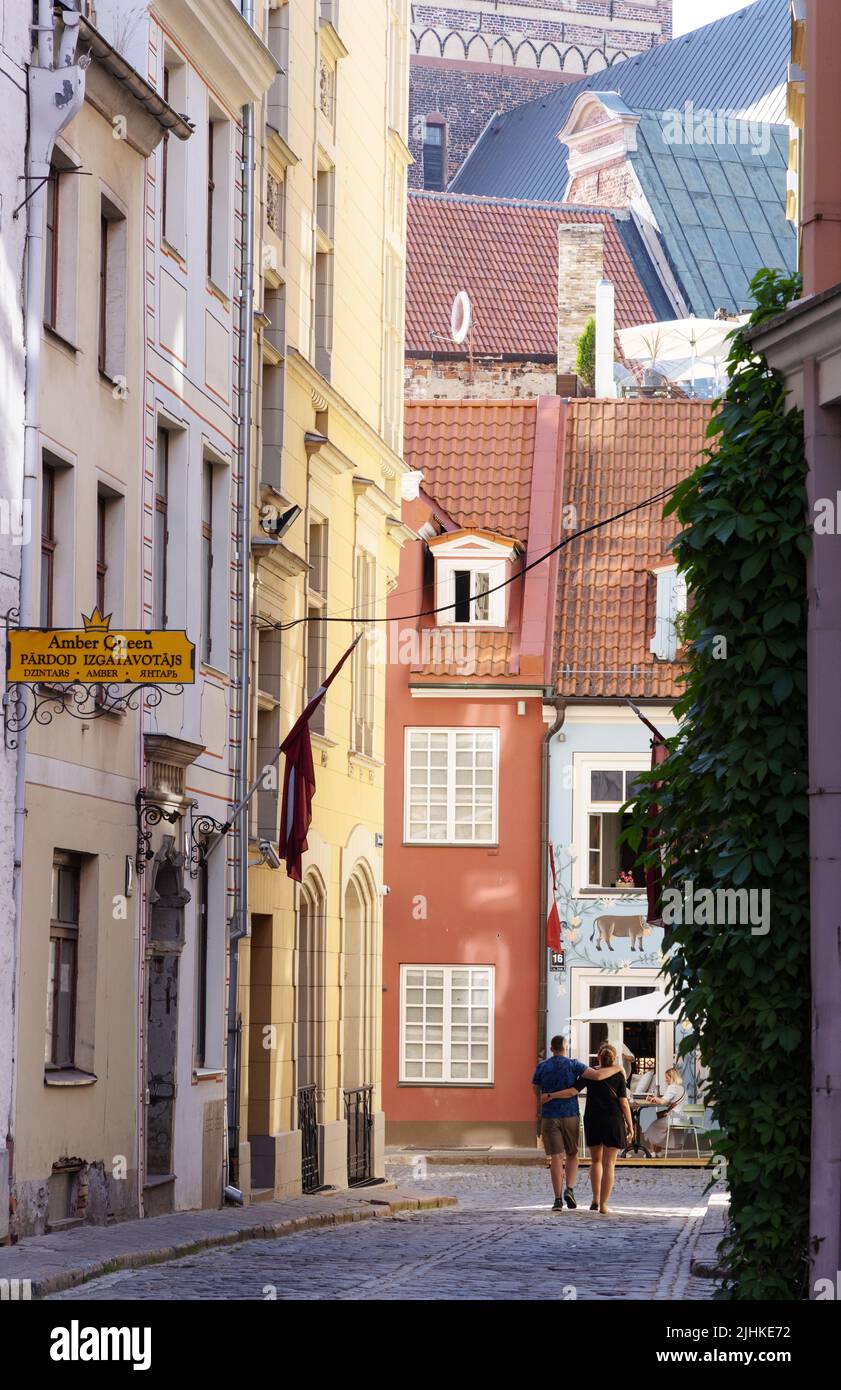 Riga Lettonia; una coppia che cammina in una scena di strada acciottolata nelle strette strade della città vecchia di riga, riga, Lettonia Europa Foto Stock
