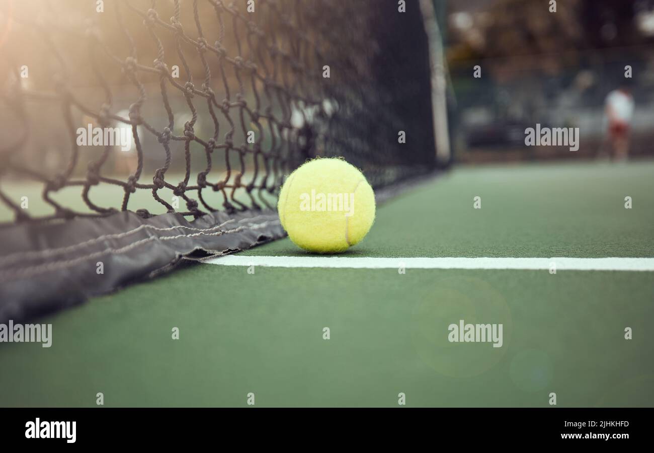 Primo piano di una palla da tennis gialla sul pavimento dopo aver colpito una rete durante una partita su un campo. Ancora la sfera di vita su una linea durante gli sport competitivi Foto Stock