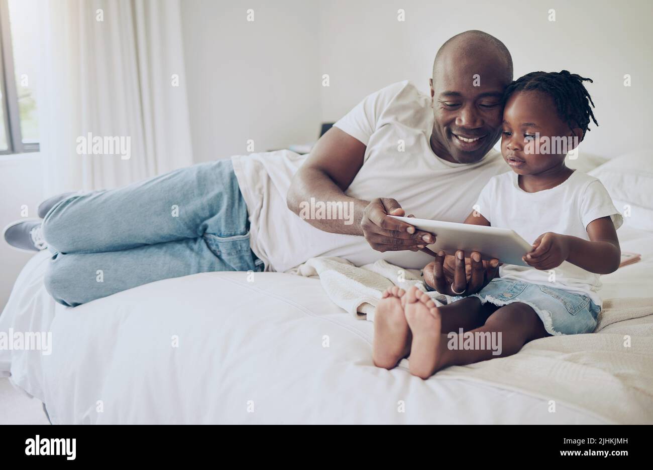 Posso guardarlo con te. Un padre e una figlia che usano un tablet digitale insieme a casa. Foto Stock