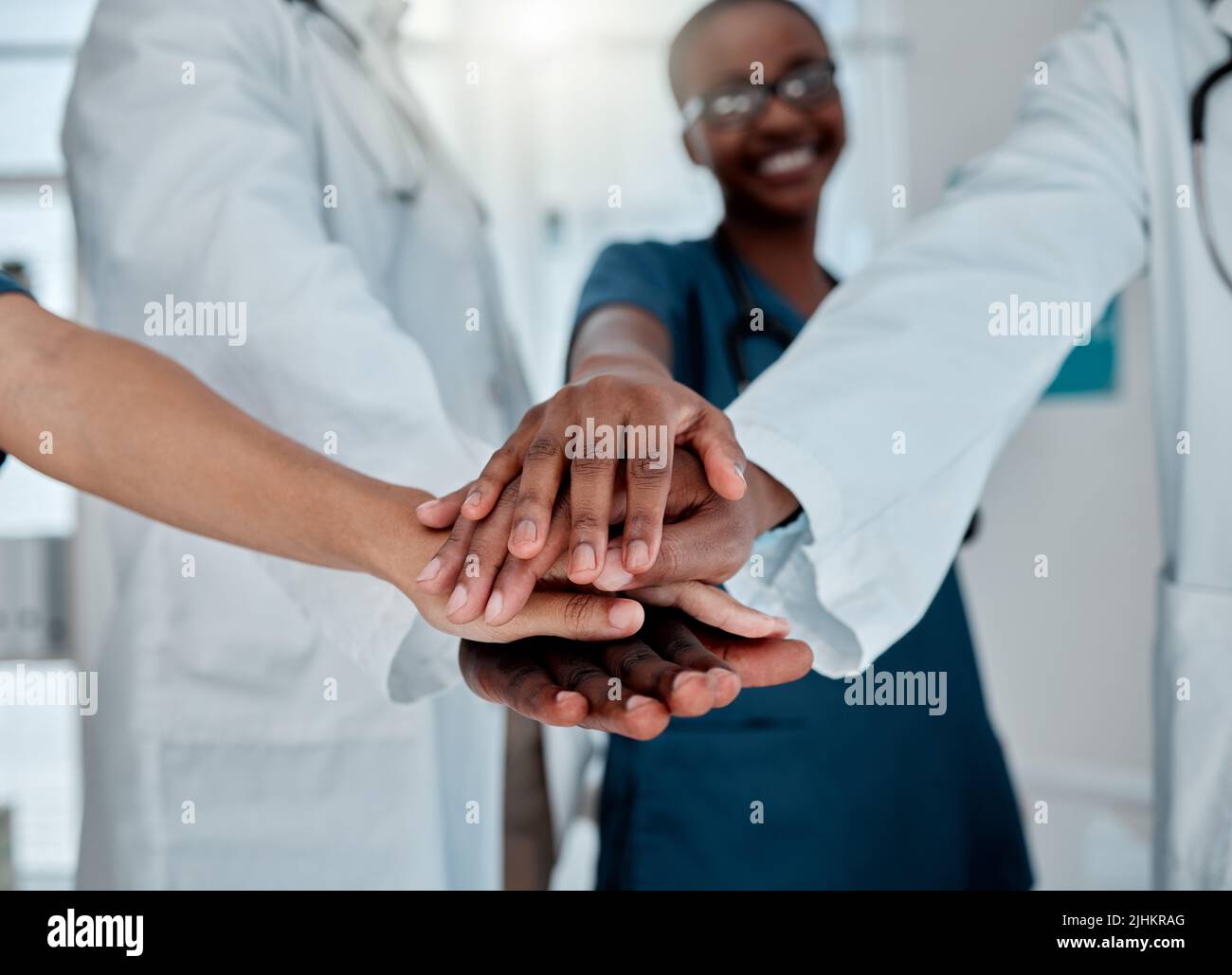 Gruppo di medici diversi che si accatastano le mani in supporto mentre lavorano in un ospedale. Professionisti medici che uniscono le loro mani in unità e. Foto Stock