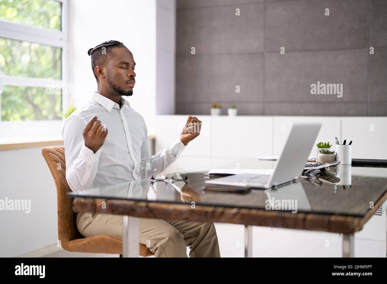 Dipendente africano che fa salute mentale meditazione Yoga in ufficio Foto Stock