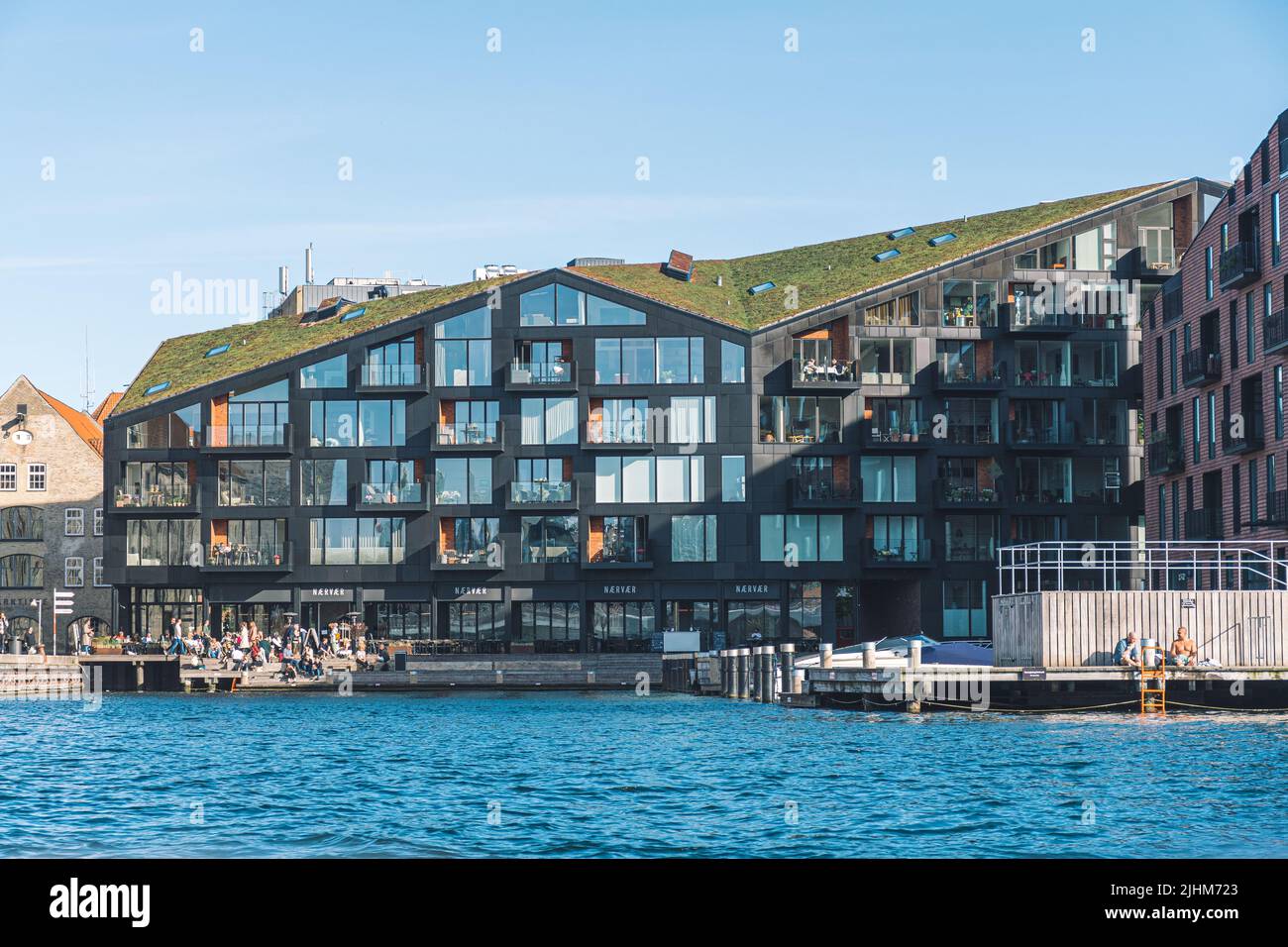 Moderni appartamenti edifici con erba sul tetto dell'isola sul canale a Copenhagen, Danimarca, con persone e turisti Foto Stock