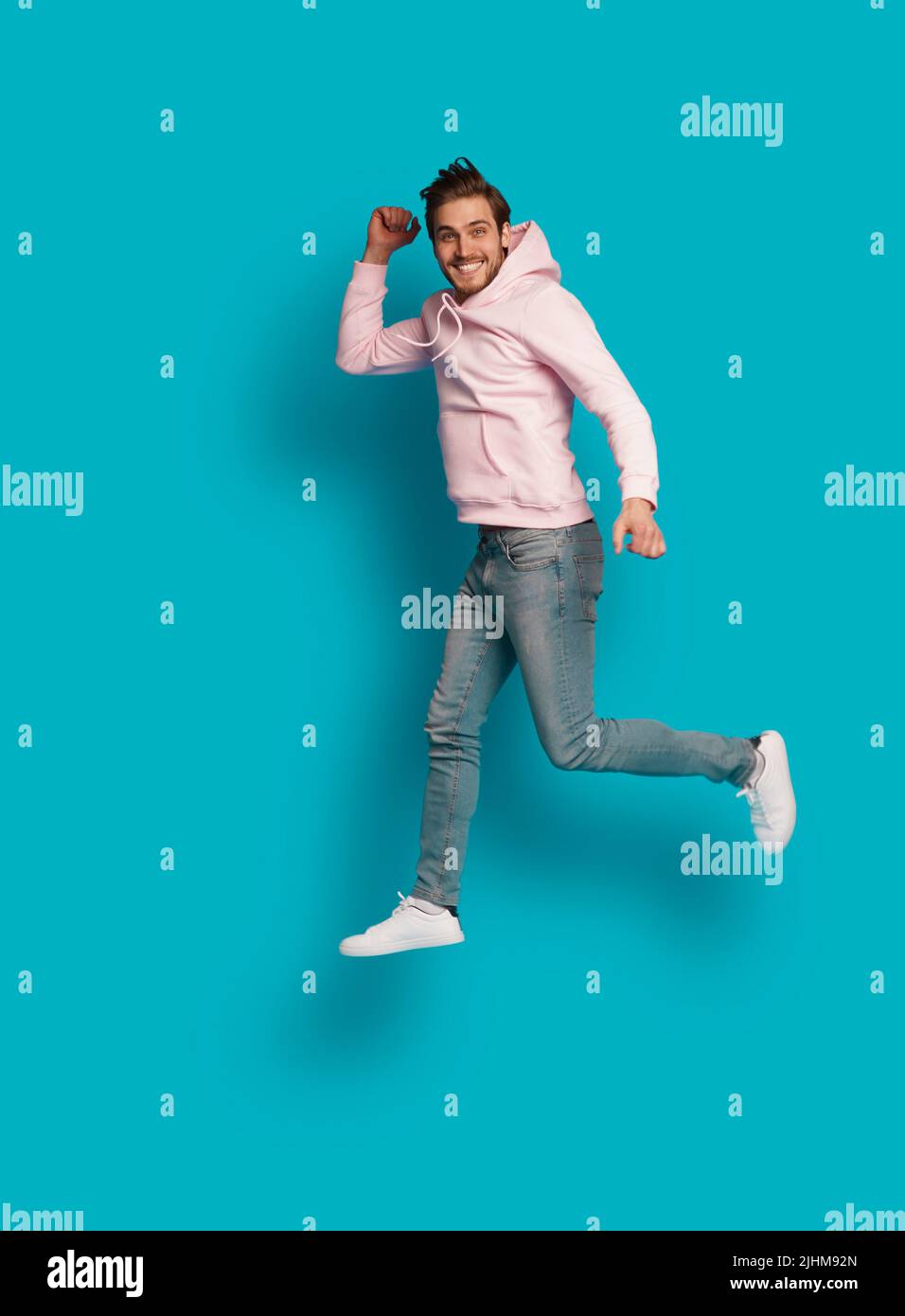 Foto a grandezza naturale di giovane felice eccitato sorridente positivo uomo che salta isolato su sfondo di colore azzurro chiaro Foto Stock