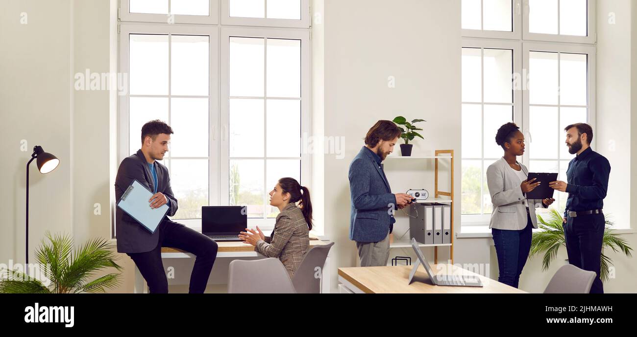 Interni dell'ufficio in cui diversi colleghi impegnati parlano, discutono e risolvono questioni di lavoro. Foto Stock