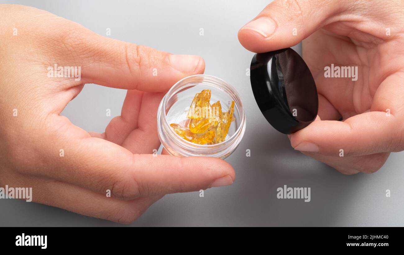 cera di cannabis dorata in mani femminili in una scatola, estratto forte di thc. Foto Stock