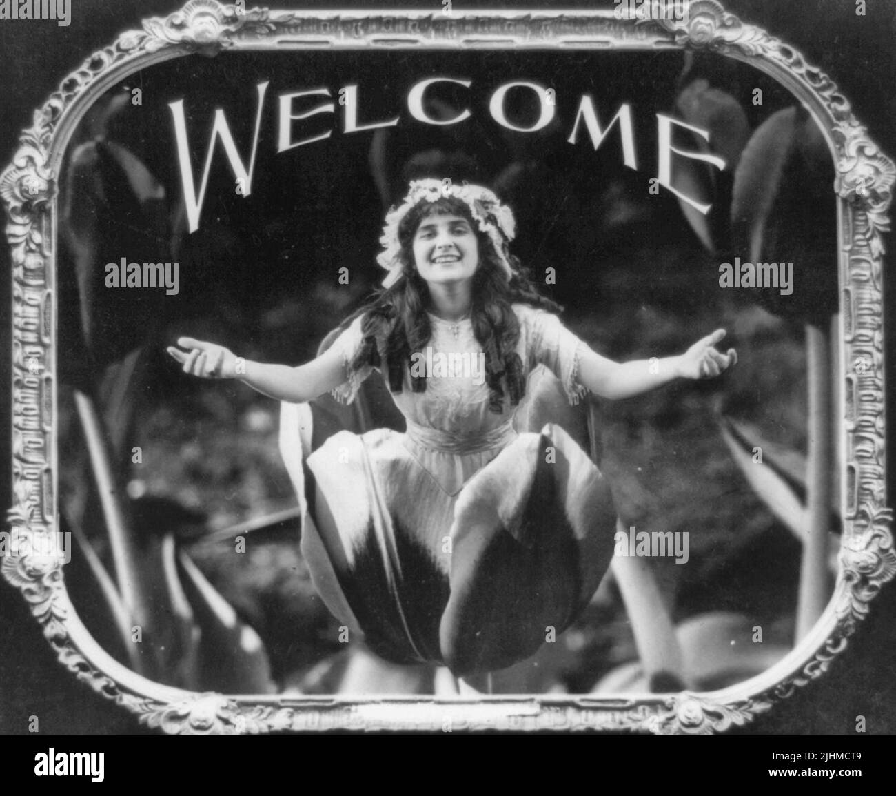 Benvenuto - la foto mostra una donna a braccia aperte che sembra alzarsi da un fiore di tulipano di apertura. Stampa su carta positiva da slide lanterna utilizzata nelle sale cinematografiche come annuncio. Foto Stock