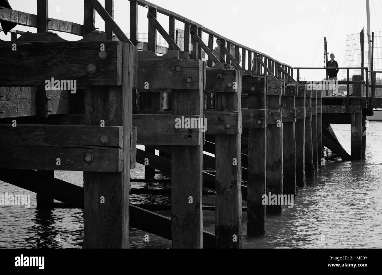 Ragazzo in piedi sul molo di legno a Lake Pier Beach sulla costa settentrionale di Poole Harbour, Regno Unito Foto Stock