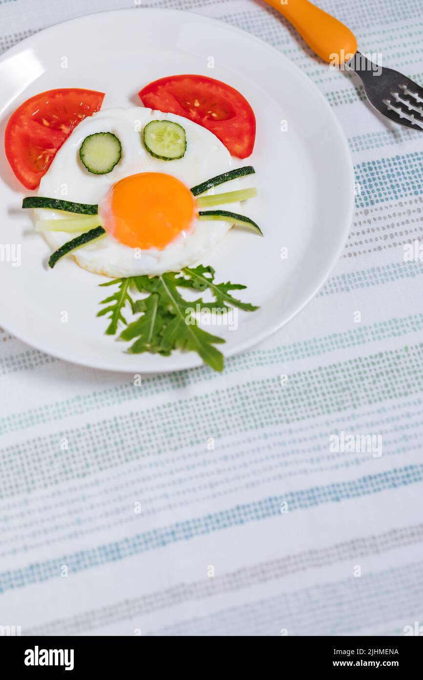 Colazione all'uovo con lato soleggiato, decorata per i bambini, con carattere animale. Servito con verdure. Foto Stock