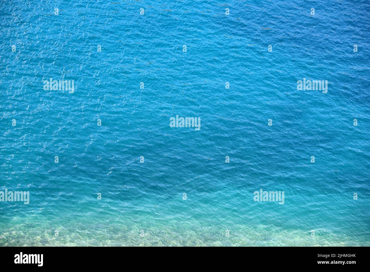 Superficie blu dell'acqua di mare con pietre sul fondo. Acqua turchese chiara per lo sfondo Foto Stock