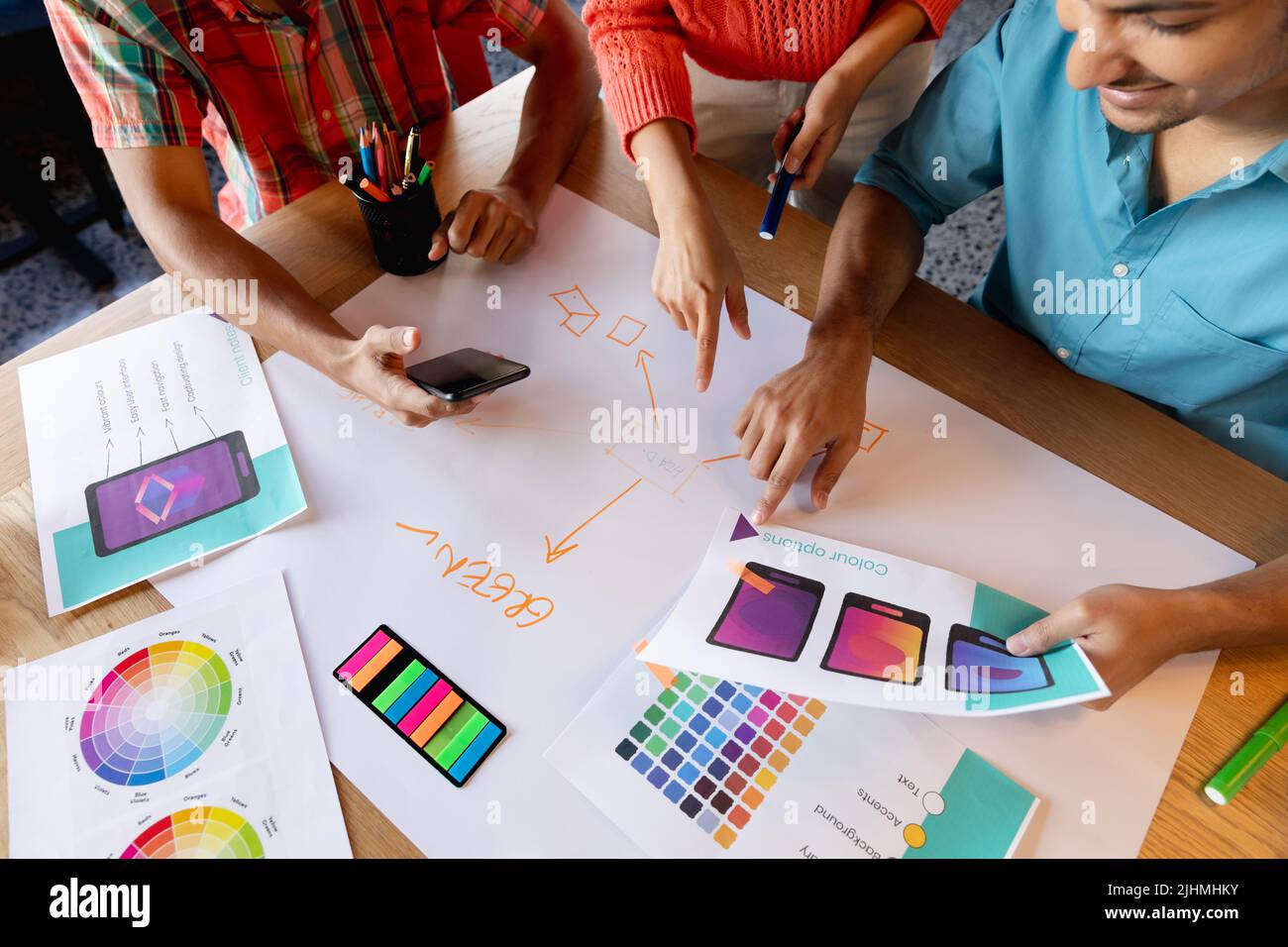 Creativi professionisti di disegno multirazziale che discutono sopra i diagrammi al tavolo in ufficio Foto Stock