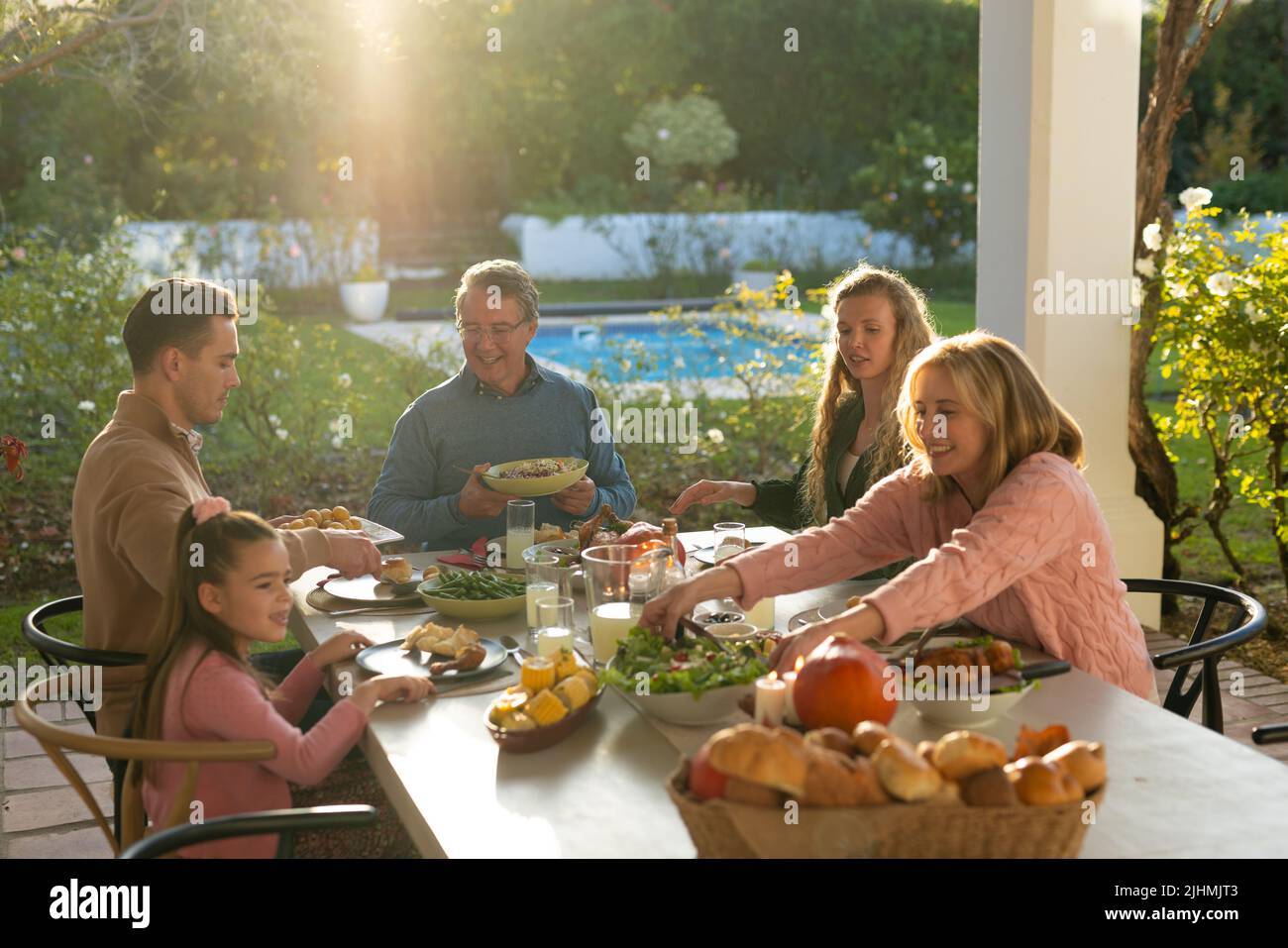 Immagine di una famiglia caucasica di più generazioni che mangia una cena all'aperto Foto Stock