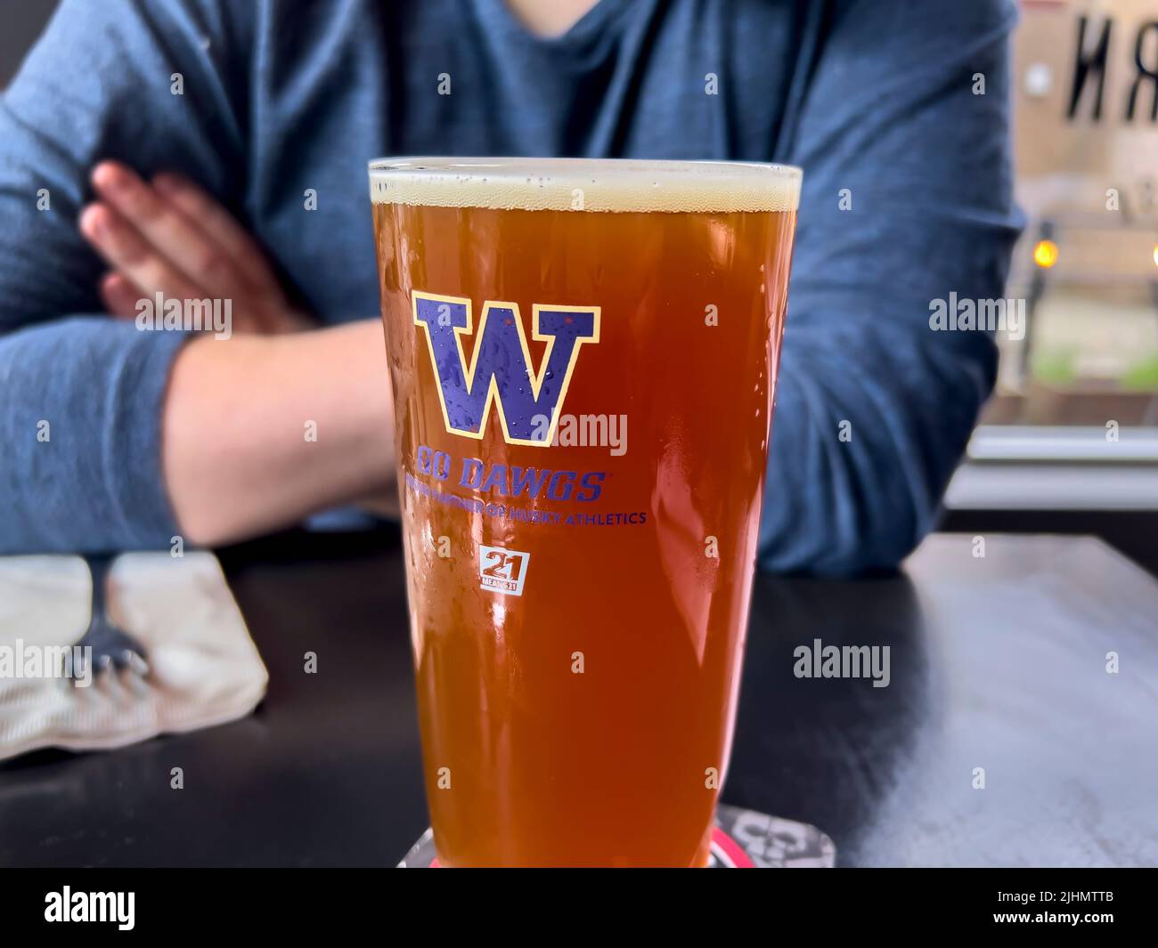 Seattle, WA USA - circa Giugno 2022: Primo piano di una birra frizzante in un bicchiere dell'Università di Washington all'interno di un bar locale. Foto Stock