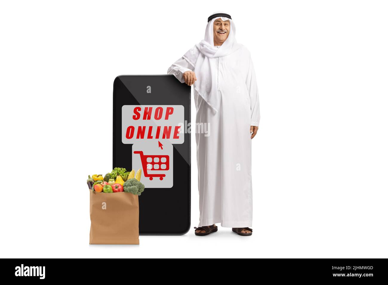 Uomo arabo in abiti etnici appoggiati su un telefono cellulare e una borsa di alimentari, negozio online concetto, isolato su sfondo bianco Foto Stock