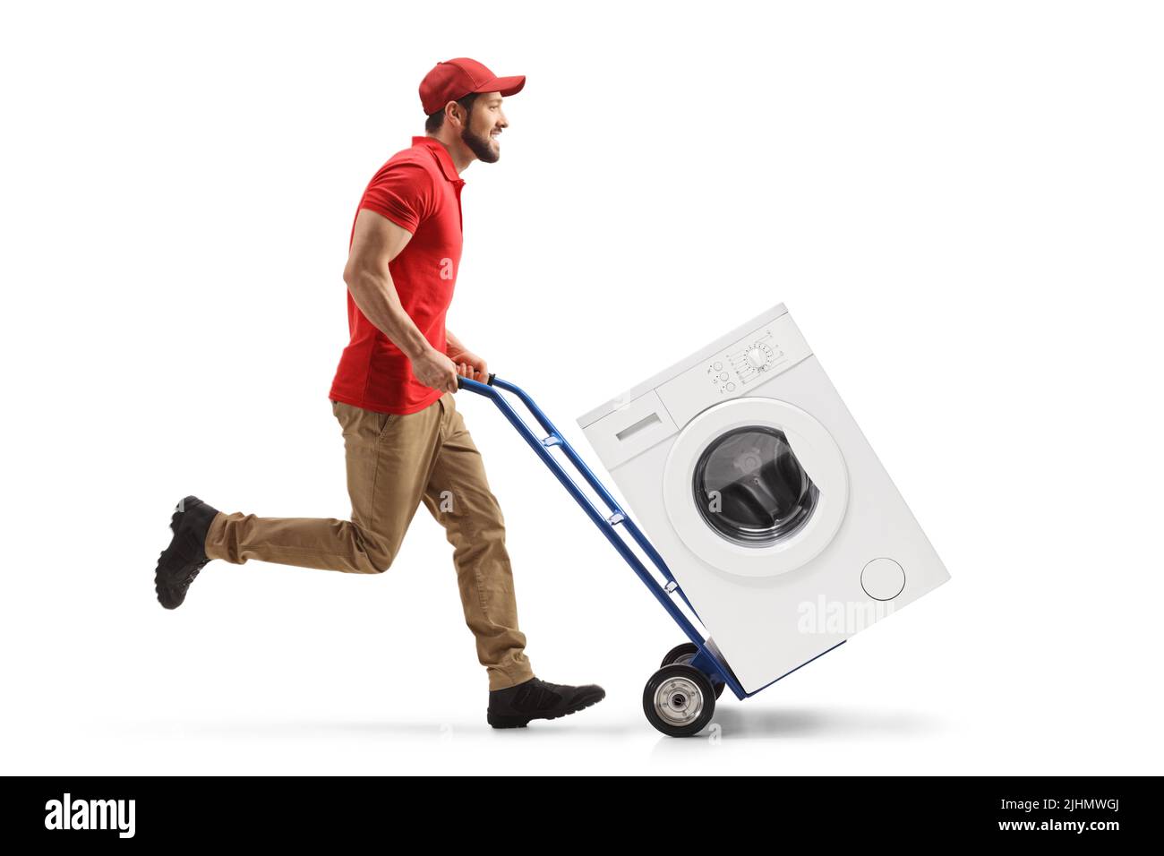 Colpo di profilo a tutta lunghezza di un lavoratore maschile che corre e spinge un camion-mano con una lavatrice isolata su sfondo bianco Foto Stock