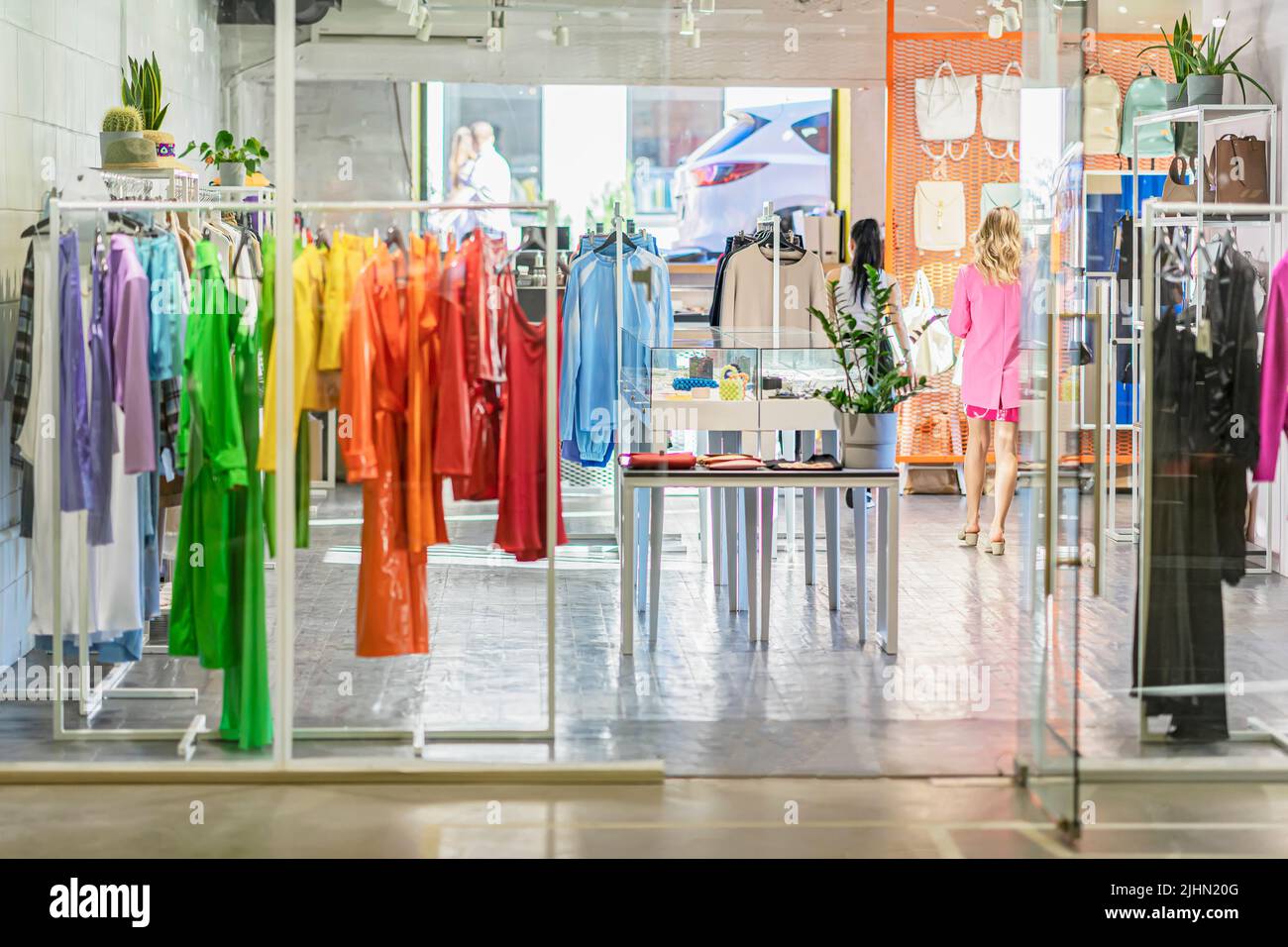 Vestiti colorati su appendiabiti, assortimento in negozio di abbigliamento leggero, shopping stagionale. Scelta di abbigliamento in colori vivaci Foto Stock