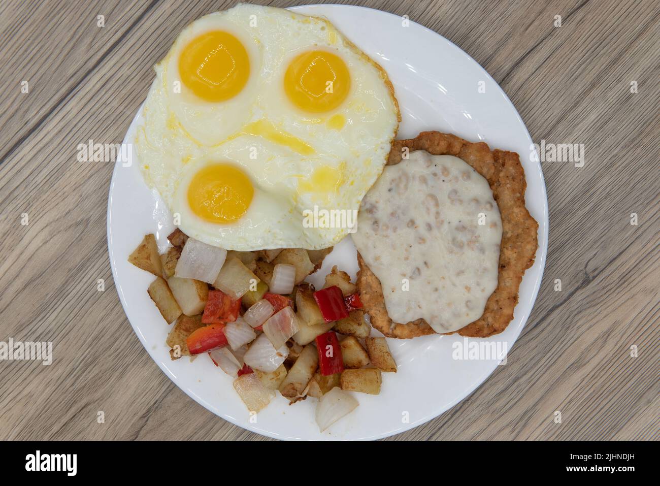 La vista dall'alto della colazione americana standard, che comprende bistecca di pollo fritta, crostata con sugo di carne, uova fritte e patate condite, assicurerà che Foto Stock