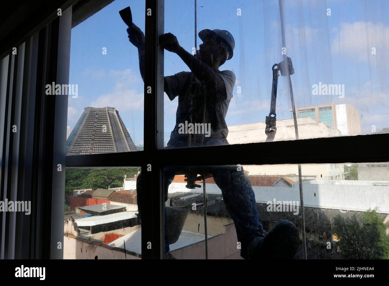 Rappeling uomo lavoro sul servizio di pulizia di finestre esterne e riparazione di edifici. Lavoro rapel ristrutturazione edificio. Carpentiere di costruzione lavoratore Foto Stock