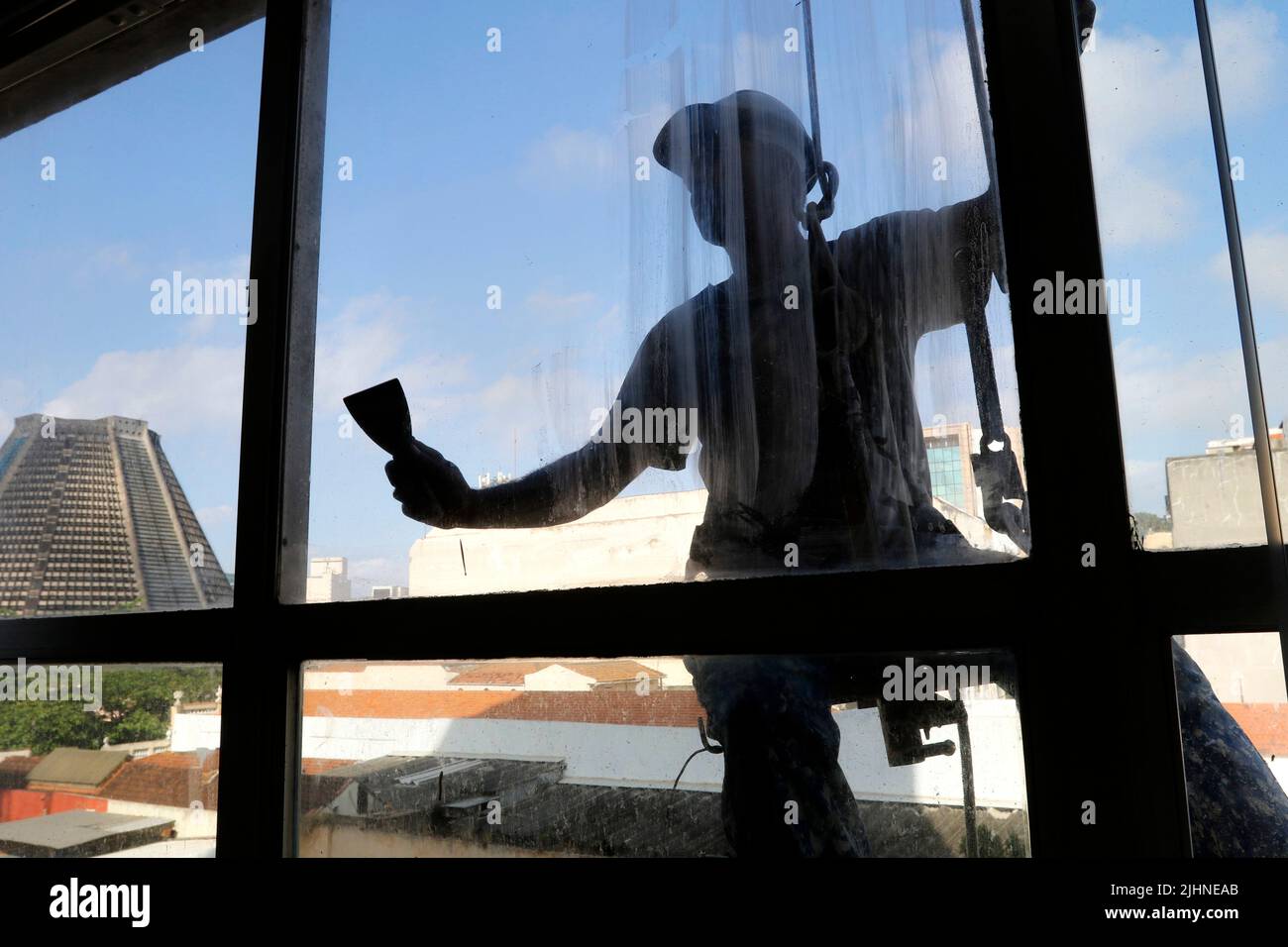 Rappeling uomo lavoro sul servizio di pulizia di finestre esterne e riparazione di edifici. Lavoro rapel ristrutturazione edificio. Carpentiere di costruzione lavoratore Foto Stock