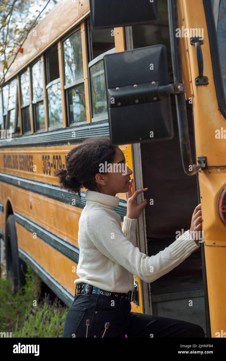 Studente della scuola elementare salire sul bus della scuola per andare in classe Foto Stock