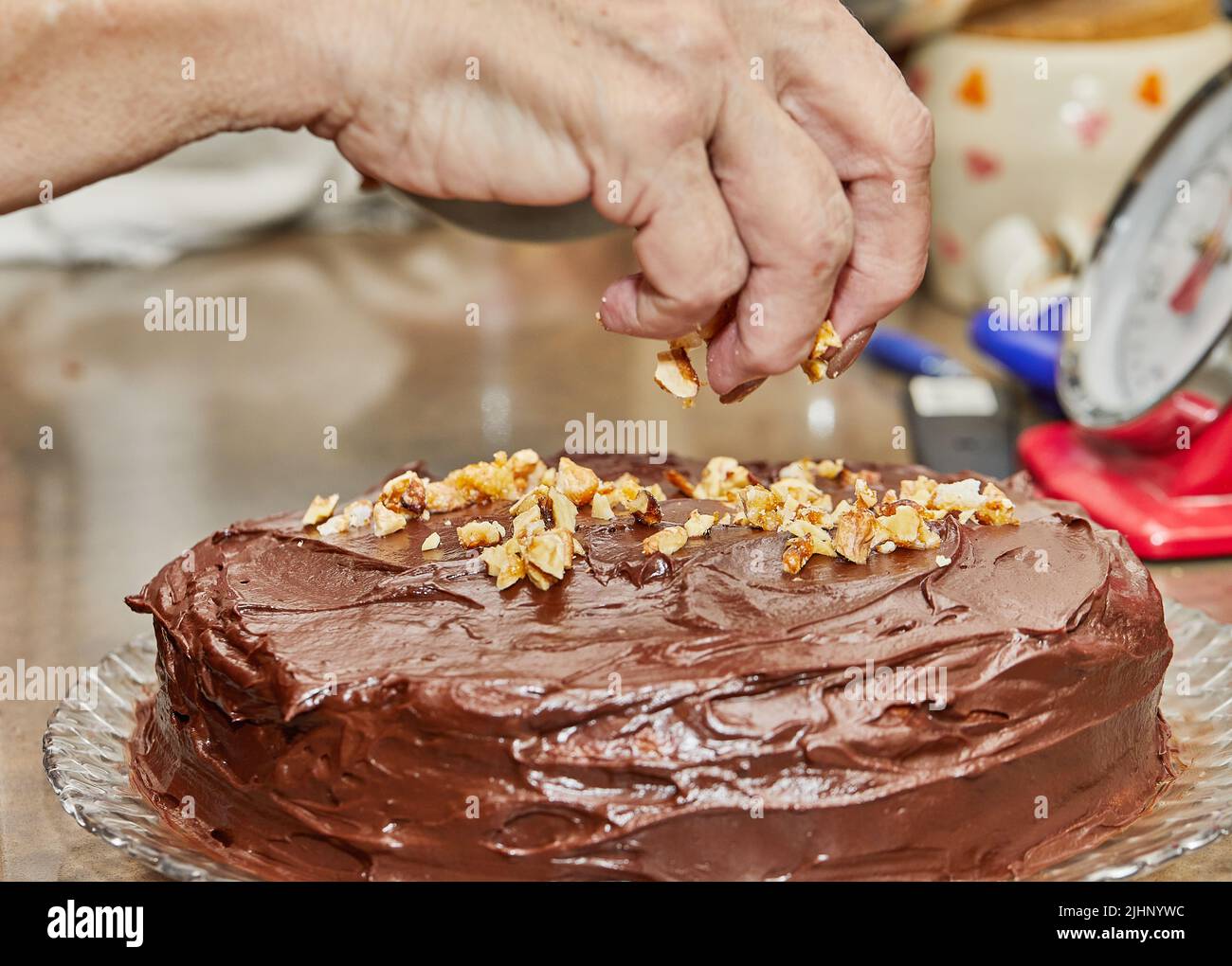 Lo chef cosparge le noci sulla torta per preparare la torta al cioccolato con pere e noci Foto Stock
