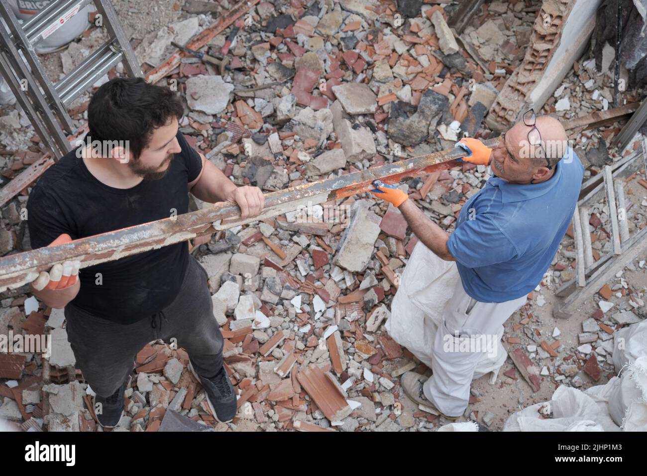 Due lavoratori che rimuovono vecchie travi di metallo in una casa di costruzione. Foto Stock