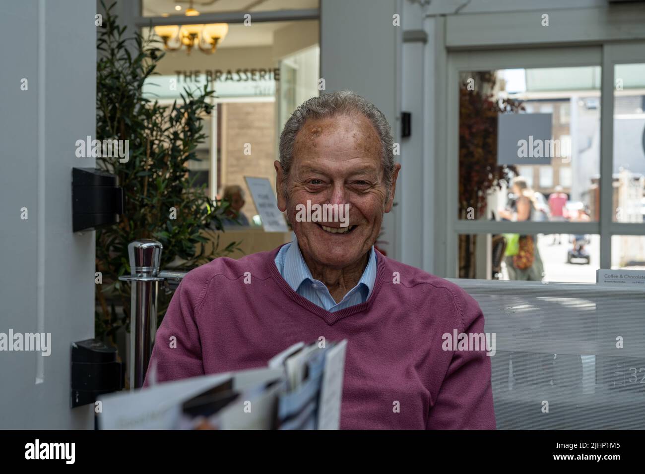 Anziano uomo maturo che guarda felice, e allegro in un caffè del centro della città. Foto Stock
