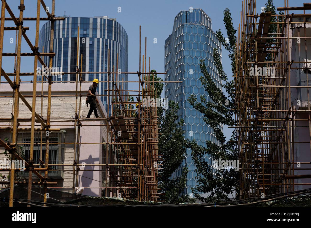 Un lavoratore cammina su un ponteggio in un cantiere di costruzione di un edificio di appartamenti in fase di ristrutturazione a Pechino, Cina, 20 luglio 2022. REUTERS/Thomas Peter Foto Stock