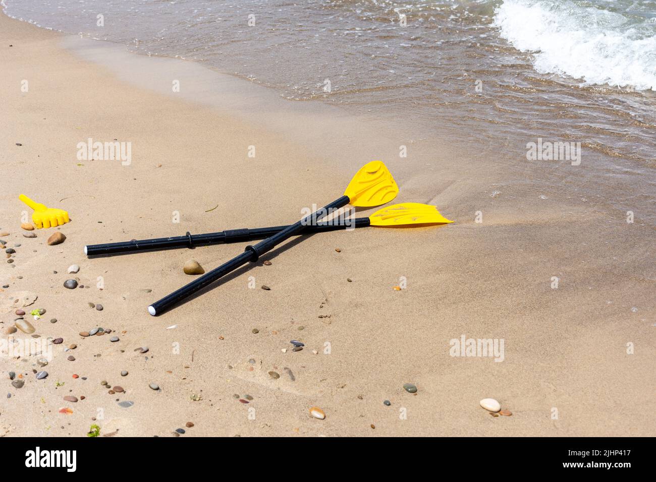 Pagaia gialla in kayak sulla spiaggia di ciottoli. Attrezzatura sportiva per kayak. Foto Stock