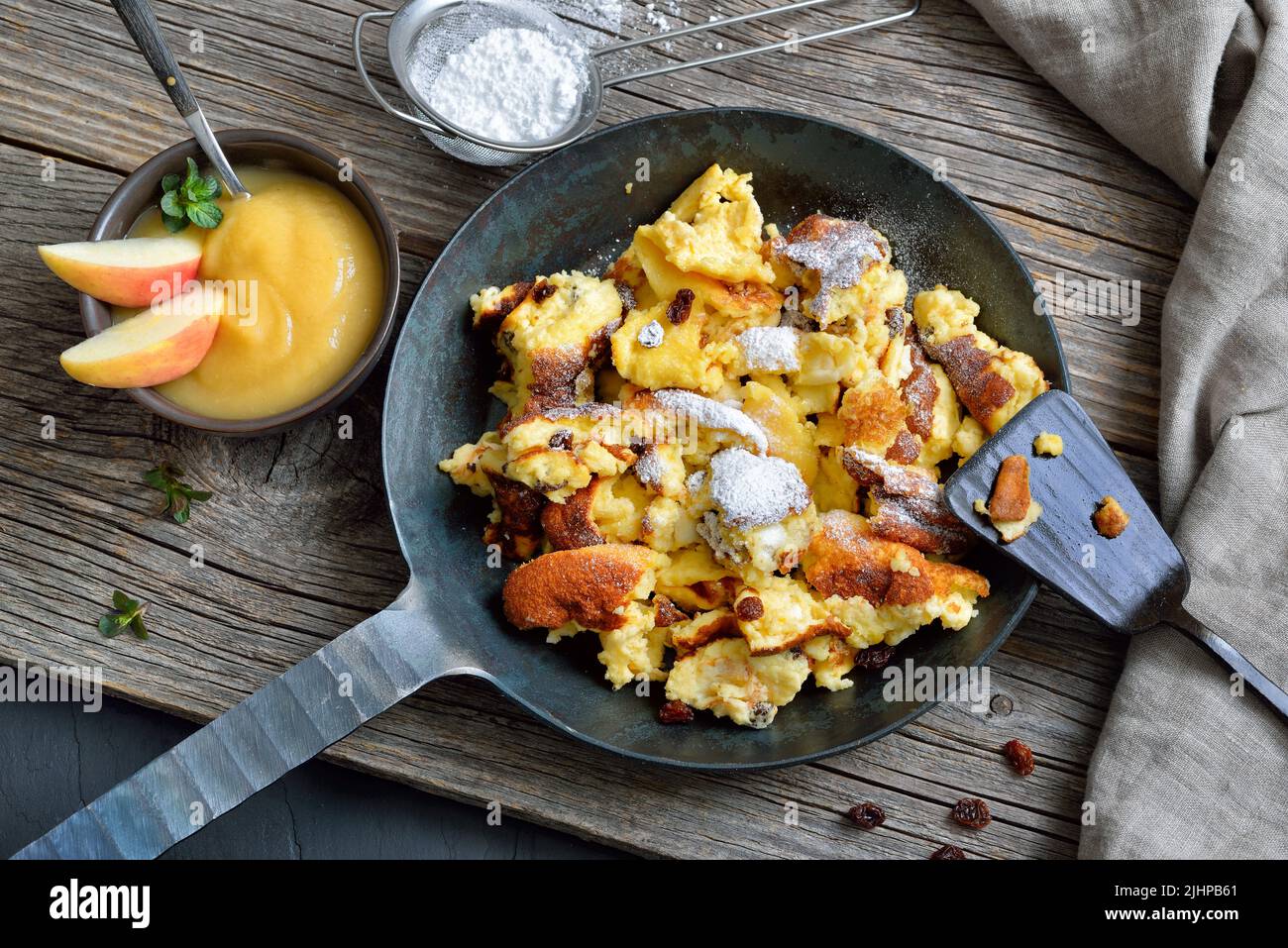 Kaiserschmarrn viennese tradizionale, frittelle dolci grattugiate con uva passa, servite in una padella di ferro su vecchi assi di legno su un piatto di ardesia Foto Stock
