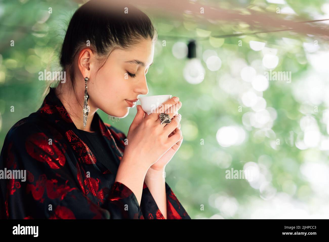 Shot di giovane donna che beve dalla ciotola del tè Foto Stock