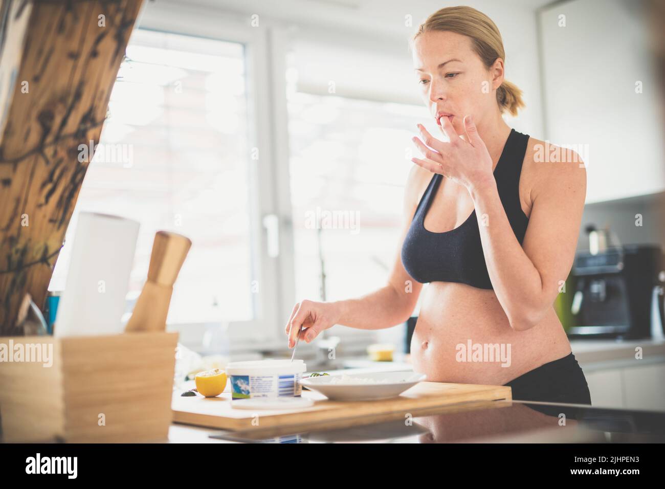 Bella sportivo in forma giovane donna incinta preparare pasto sano in cucina a casa. Concetto di stile di vita salutare. Foto Stock