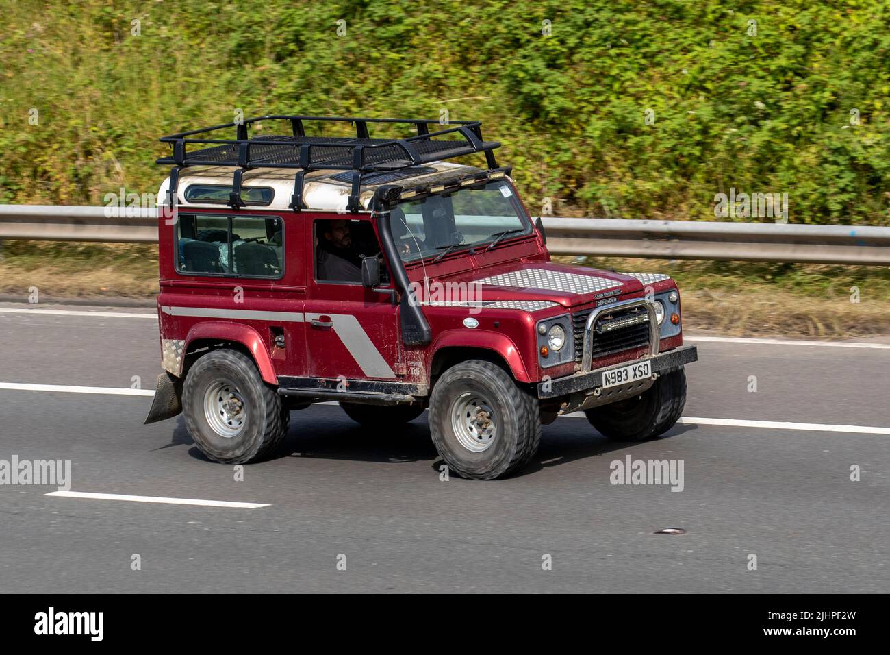 1996 90s anni '90 Red LAND ROVER Defender HT TDi 95; viaggiando sull'autostrada M6, Manchester, Regno Unito Foto Stock