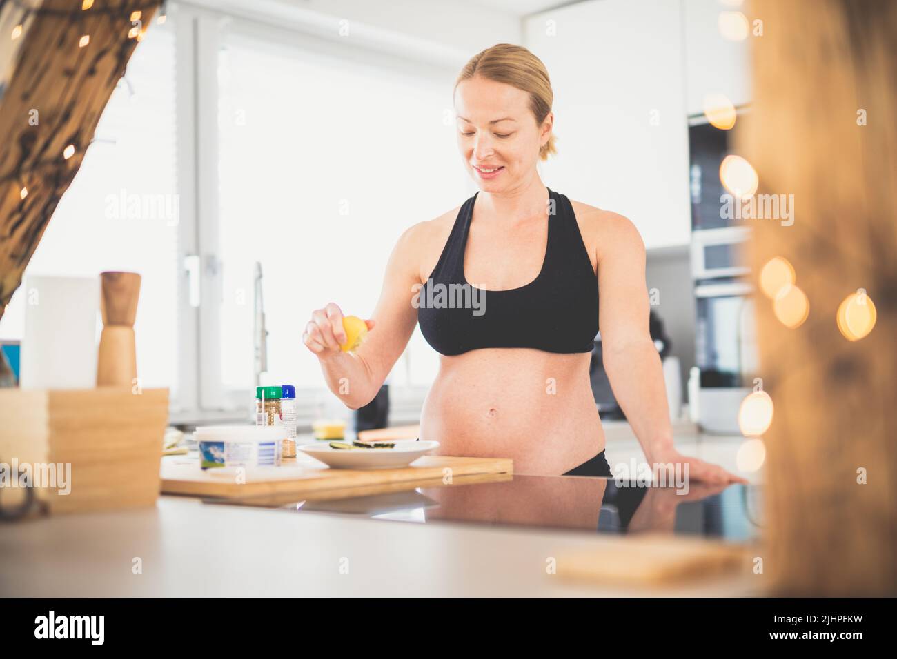 Bella sportivo in forma giovane donna incinta preparare pasto sano in cucina a casa. Concetto di stile di vita salutare. Foto Stock