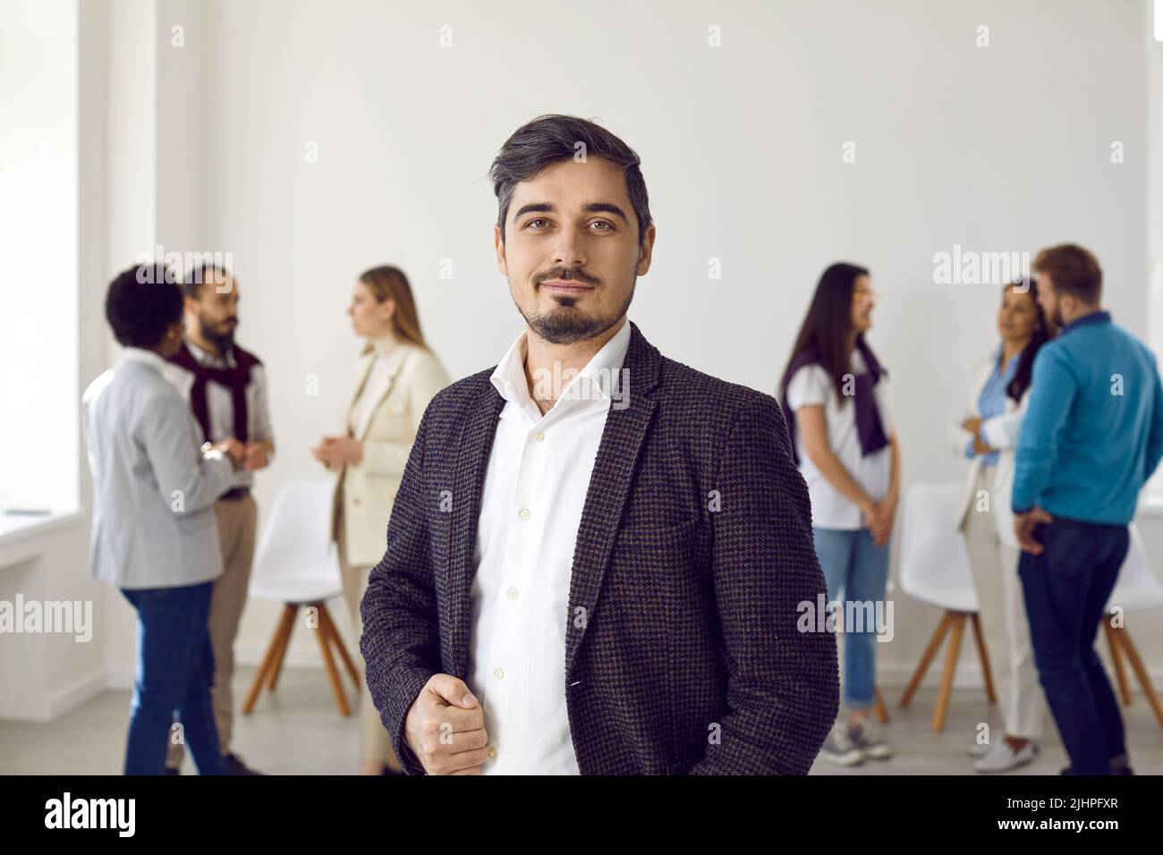 Affascinante uomo d'affari che si pone di fronte alla sua squadra multietnica su uno sfondo bianco Foto Stock