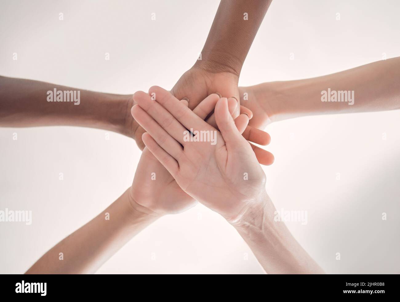 Gruppo di uomini d'affari diversi che si accumulano le mani insieme in un ufficio al lavoro. Professionisti aziendali che si divertono in piedi con le mani impilate Foto Stock