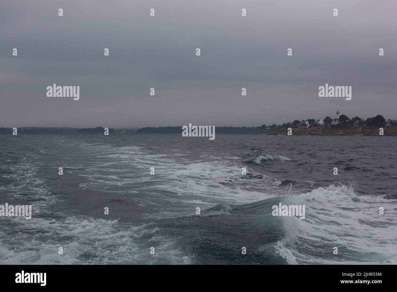 il motore della barca lascia un sentiero bianco sull'oceano. Il tempo è molto coperto, le onde aumentano sull'oceano. Foto Stock