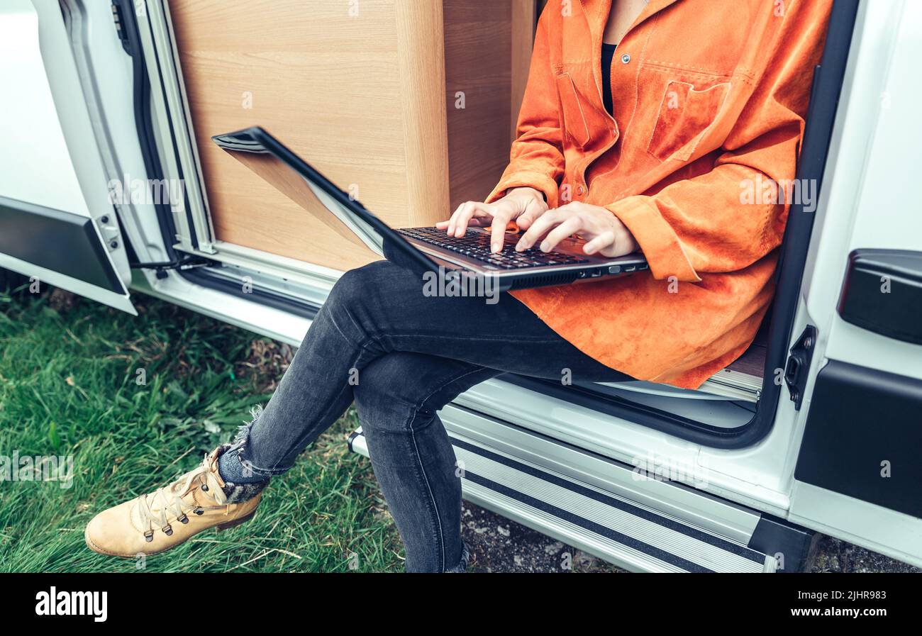 Donna telelavoro seduta alla porta del camper Foto Stock