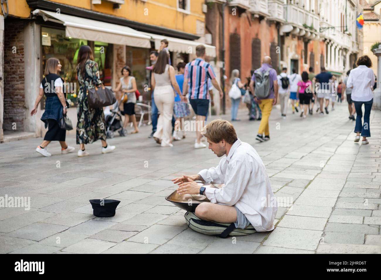 VENEZIA, ITALIA - 22 MAGGIO 2022: Musicista di strada che suona appendere vicino a cappello sulla strada urbana Foto Stock