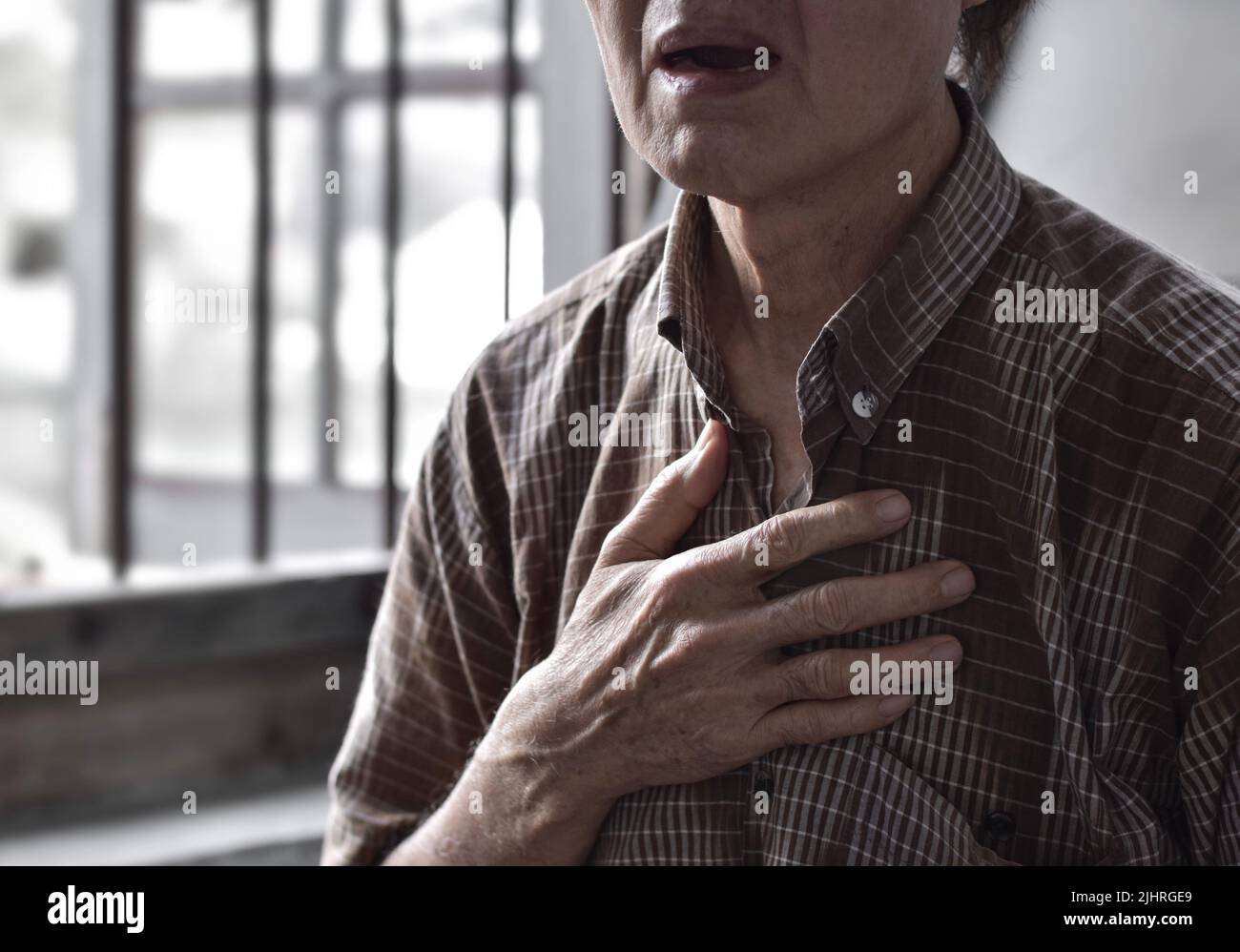 L'anziano asiatico soffre di senso di costrizione toracica. Può essere causato da asma, bronchite, bronchiolite, polmonite, infarto miocardico, h ischemica Foto Stock