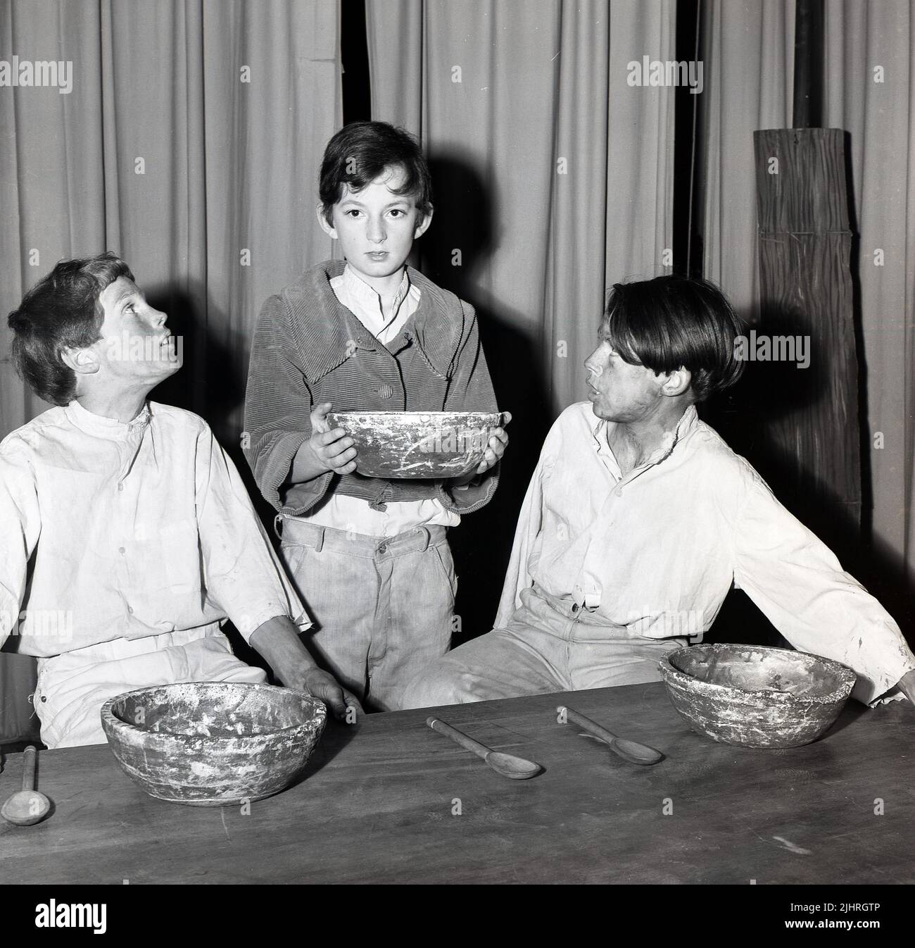 1970s, storico, tre bambini attori maschi con bocce che si esibiscono nel musical di scena, Oliver, Inghilterra, Regno Unito. Scritto da Lionel Bart, il palcoscenico di prossima generazione si basa sul romanzo del 1838 'Oliver Twist', del famoso drammaturgo inglese Charles Dickens. Il carattere geniale è Oliver, un ragazzo malnutrito, un orfano in una casa di lavoro, che, dopo essere stato apprendista da un undertaker, fugge a Londra dove si mescola con piccoli ladri e sottaceti. Foto Stock
